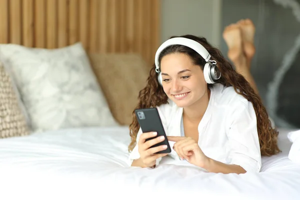Женщина Использует Смартфон Наушниках Слушать Музыку Лежащую Кровати — стоковое фото