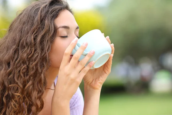 公園でマグカップからコーヒーを飲む女性 — ストック写真
