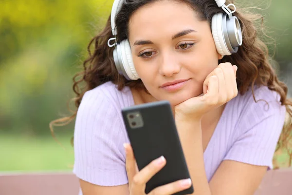 Žena Poslouchá Hudbu Sluchátky Parku Kontroluje Telefon — Stock fotografie