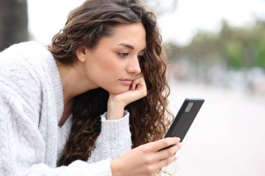 Sokakta oturan akıllı telefonu kullanan ciddi bir kadın.