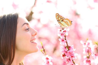 Tarlada kelebeğe bakan mutlu bir kadının profili.