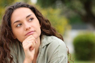 Parkta yan tarafa bakan düşünceli bir kadının portresi.