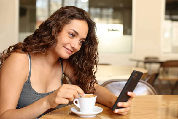 Mujer Revisando Teléfono Inteligente Revolviendo Café Sentado Bar — Foto de Stock