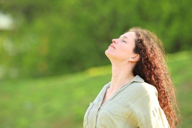 Woman breathing fresh air in green background