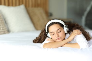 Woman sleeping listening to music lying on a bed in the bedroom