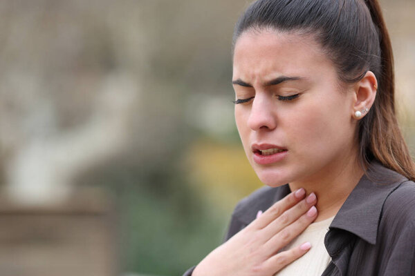 Woman complaining suffering throat ache standing in a park