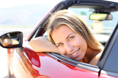 Happy convertible car driver looks at you smiling