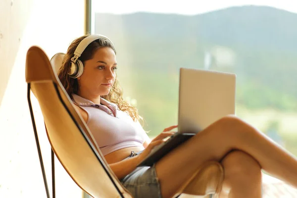 Serious woman with headphones checks laptop at home