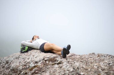 Hiker resting lying on a rock in the mountain a foggy day