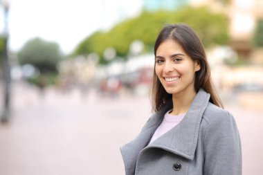Happy woman looks at camera standing in the street in winter