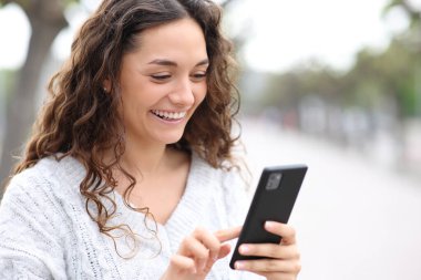 Sokakta cep telefonu kullanan mutlu bir kadın.