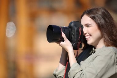 Dışarıda fotoğraf çeken mutlu bir fotoğrafçının yan görünümü