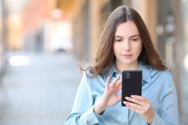 Sokakta telefonla dolaşan ciddi bir kadının portresi.