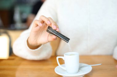 Barda kahve fincanına parmak işareti yapan bir kadının yakın portresi.