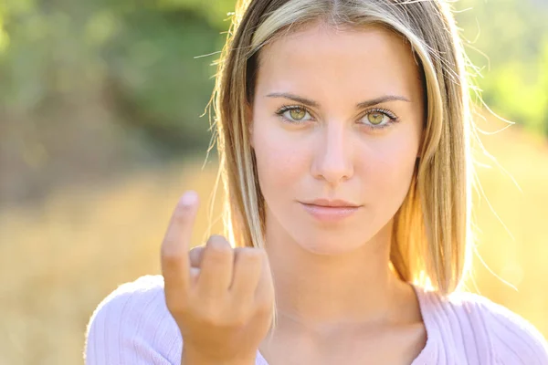 Front view portrait of a beautiful woman with yellow eyes gesturing come here in nature