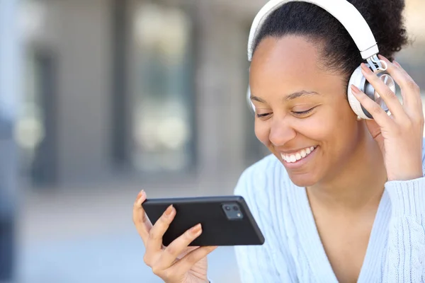 Szczęśliwy Czarny Kobieta Noszenie Słuchawki Oglądanie Filmów Poziomym Smartfona Ulicy — Zdjęcie stockowe