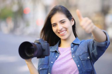 Happy photographer gesturing thumb up in the street clipart