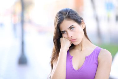 Sıkıcı kadın sokakta dikilip yan tarafa bakıyor.