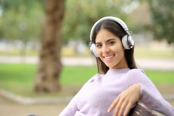 Счастливая Женщина Слушающая Музыку Смотрящая Камеру Сидящую Скамейке Парке — стоковое фото