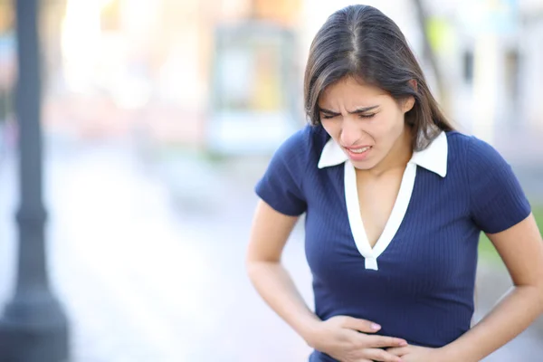 Woman suffering belly ache walking in the street