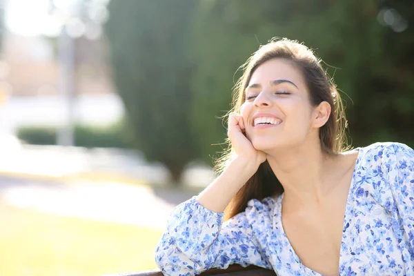 公園のベンチに座って笑っている幸せな女性 — ストック写真