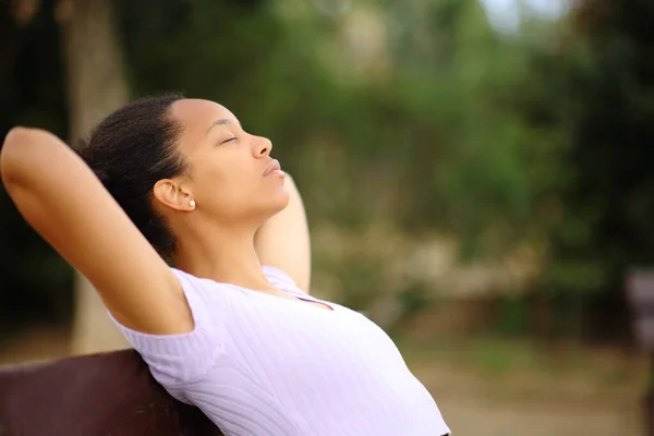 公園に座っている頭の上に手で休んでいるリラックスした黒人女性のプロフィール — ストック写真