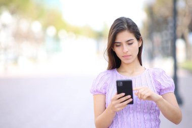 Sokakta cep telefonuyla yürüyen bir kadının görüntüsü.