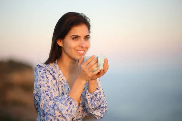 快乐的女人想在日落时分在海滩上举着咖啡杯 — 图库照片