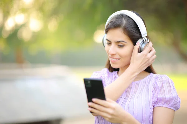 Kobieta Umieszczenie Słuchawki Oglądanie Treści Telefonu Parku — Zdjęcie stockowe