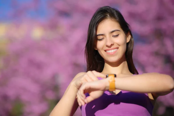 紫の公園でスマートウォッチを使用して幸せな女性のフロントビューの肖像画 — ストック写真