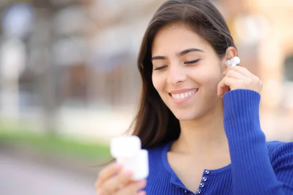 路上で耳に無線のイヤホンを置く幸せな女性 — ストック写真