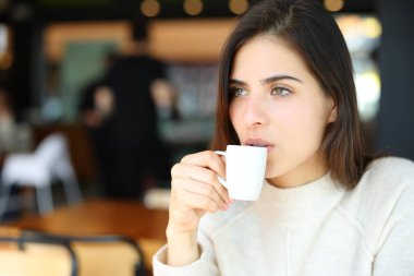 Ciddi bir kadın barda tek başına kahve içiyor ve başka tarafa bakıyor.