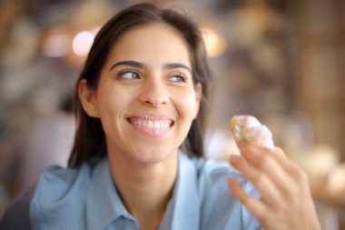 Kirli dudaklarıyla kruvasan yiyen mutlu restoran müşterisi gözlerini kaçırıyor.