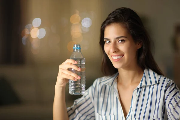 Mujer Feliz Posando Sosteniendo Botella Agua Mirando Cámara Casa Noche — Foto de Stock