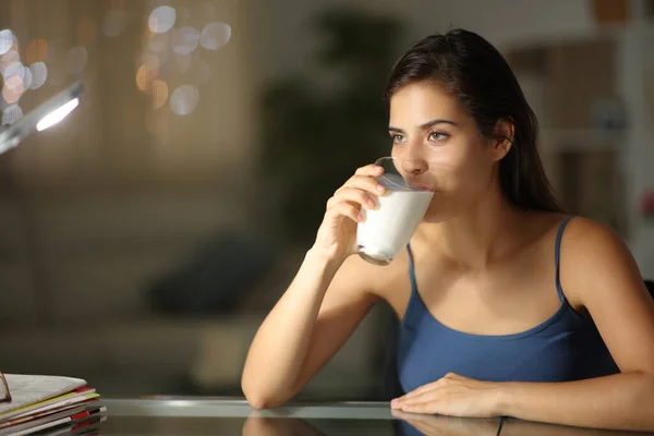 女人在夜里喝牛奶在家里朝外看 — 图库照片