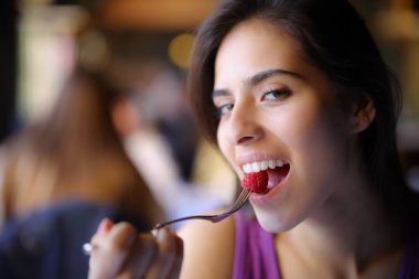 Bar içinde böğürtlen yiyen mutlu bir kadın.