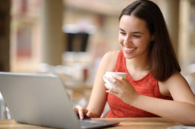 Mutlu kadın bir kafede dizüstü bilgisayar kullanıyor.