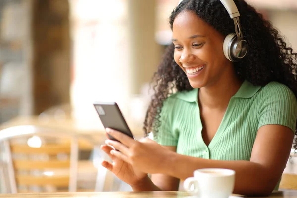 Felice Donna Nera Ascoltando Audiolibro Indossare Cuffie Controllare Smartphone Ristorante — Foto Stock