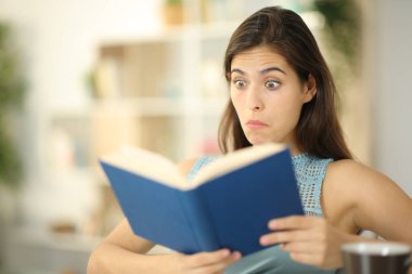 Kafası karışmış kitap okuyucu evde oturuyor