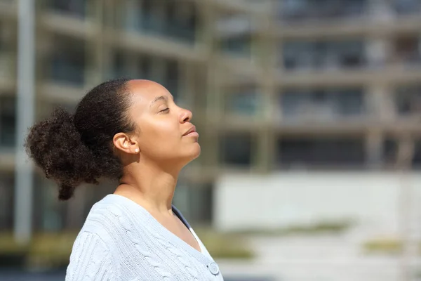 Profile of a black woman breathing fresh air in urban scene a sunny day