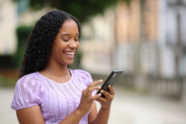 Szczęśliwy Czarny Kobieta Pomocą Smartfona Spacery Ulicy — Zdjęcie stockowe