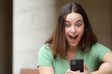 Şaşırmış bir kadının ön manzara portresi sokakta şaşırtıcı içerikleri kontrol ediyor.