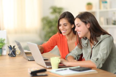 Two happy teleworkers working at home with laptops clipart