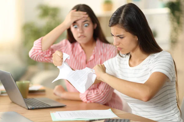 Angry worker breaking contract beside her worried colleague at home