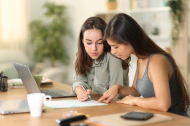 Evde okuyup kontrat imzalayan iki televizyon çalışanı.