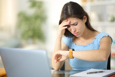 Bilgisayarlı endişeli öğrenci evde akıllı olanları kontrol ediyor.