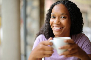 Bar terasında kahve içen mutlu siyah kadın.