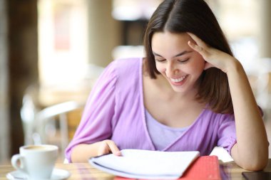 Mutlu öğrenci bar terasında notlar okuyor.