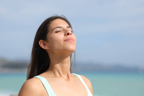 Satisfied woman breathing fresh air on the beach