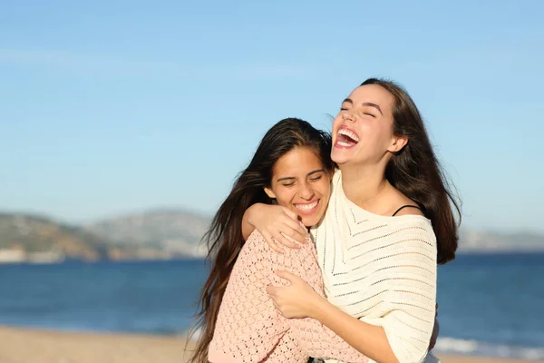 Happy friends meeting and hugging laughing very funny on the beach